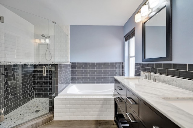 bathroom with a bath, double vanity, a sink, and a stall shower