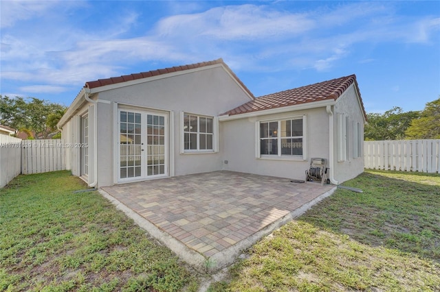 back of house featuring a yard, stucco siding, and a tiled roof