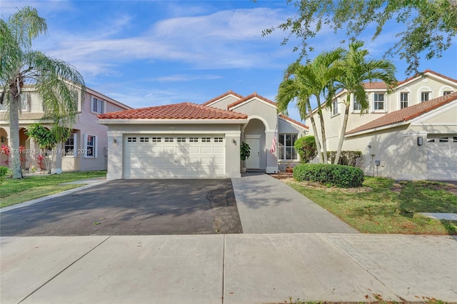 mediterranean / spanish-style home featuring a tile roof, stucco siding, a garage, and aphalt driveway