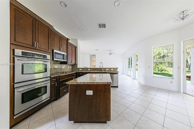4981 SW 173rd Ave, Miramar, FL 33029 - kitchen with stainless steel appliances, a sink, a center island, light tile patterned floors, and a peninsula