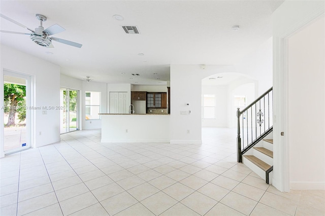 4981 SW 173rd Ave, Miramar, FL 33029 - unfurnished living room featuring arched walkways, light tile patterned floors, a ceiling fan, stairs, and baseboards