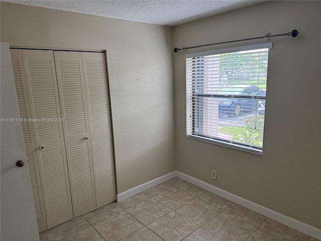 9968 Nob Hill Ct Unit 9968, Sunrise, FL 33351 - unfurnished bedroom featuring multiple windows, a closet, a textured ceiling, light tile patterned floors, and baseboards