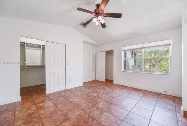 1551 Seagrape Way, Hollywood, FL 33019 - unfurnished bedroom with baseboards, a textured ceiling, two closets, and vaulted ceiling