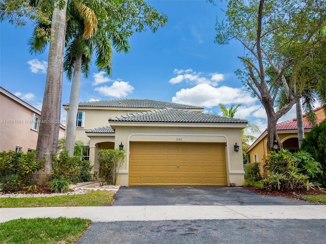 mediterranean / spanish-style house featuring an attached garage, a tiled roof, driveway, and stucco siding