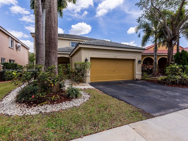 mediterranean / spanish house with an attached garage, a tile roof, stucco siding, and driveway