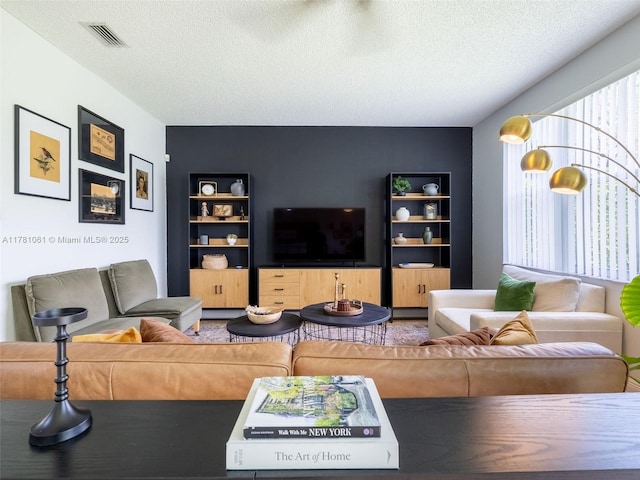 living area featuring visible vents, a textured ceiling, and built in features