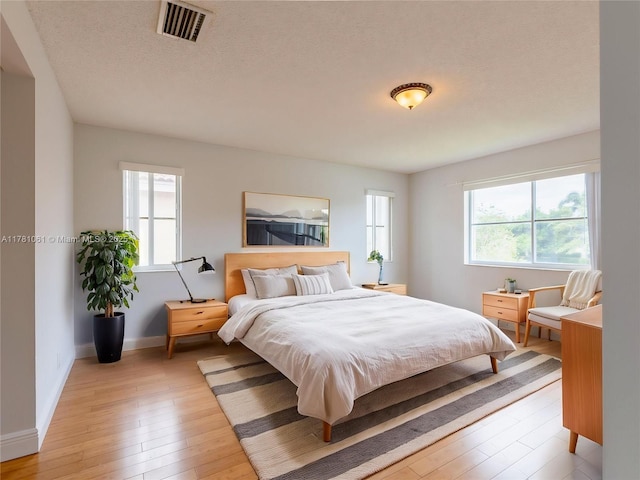 bedroom featuring light wood-type flooring, visible vents, and baseboards