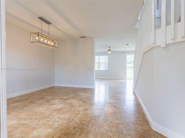 unfurnished room featuring visible vents, a ceiling fan, and baseboards