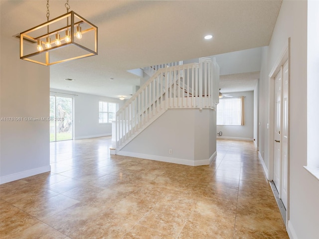interior space featuring ceiling fan with notable chandelier, baseboards, recessed lighting, and stairway