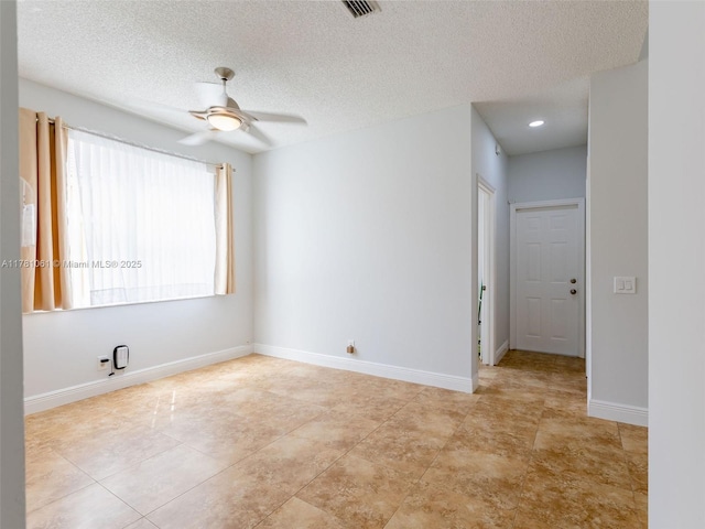 unfurnished room with a textured ceiling, light tile patterned flooring, ceiling fan, baseboards, and visible vents