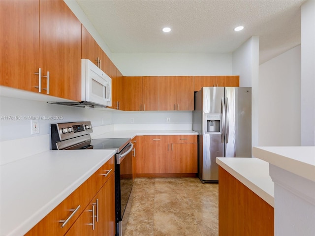 kitchen with brown cabinetry, appliances with stainless steel finishes, a textured ceiling, and light countertops