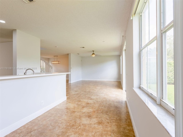 empty room featuring plenty of natural light, a textured ceiling, and baseboards
