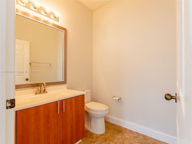 half bathroom with tile patterned flooring, toilet, vanity, and baseboards