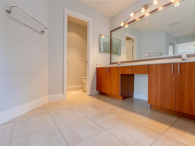 bathroom with tile patterned floors, double vanity, toilet, a sink, and baseboards