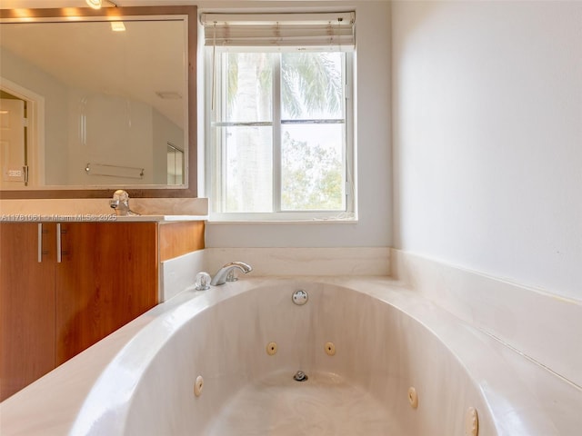 full bath with a whirlpool tub, vanity, and a healthy amount of sunlight