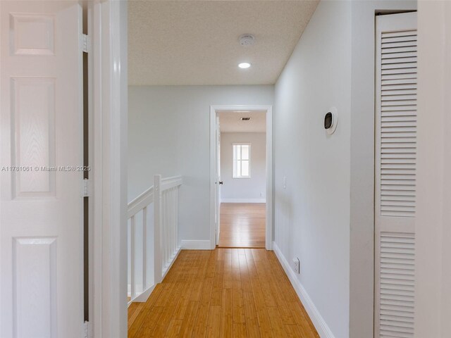 hall featuring baseboards and light wood finished floors
