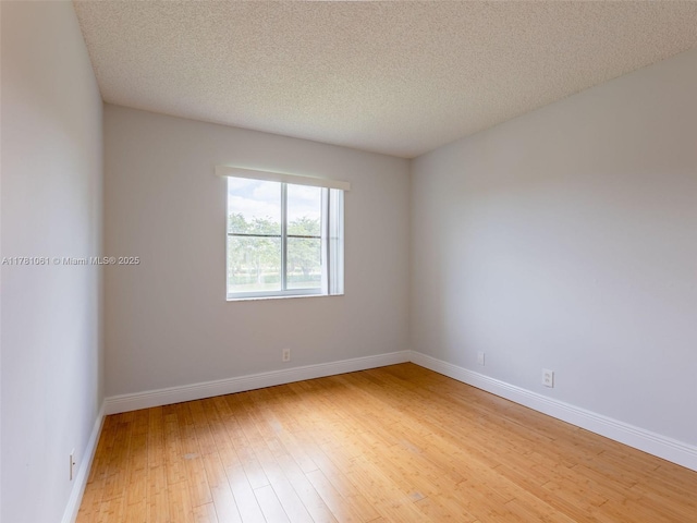 unfurnished room featuring baseboards, a textured ceiling, and light wood-style floors