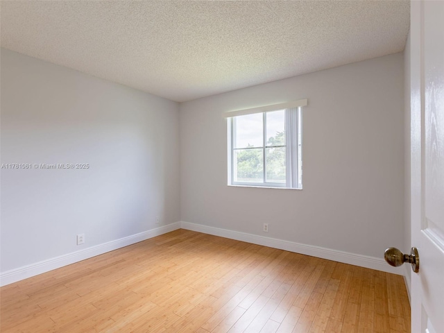 empty room with baseboards, a textured ceiling, and light wood-style flooring