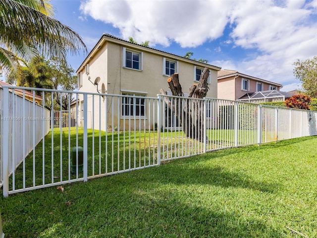 back of property featuring a lawn, a fenced backyard, and stucco siding
