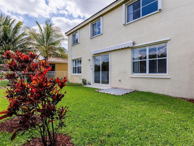 back of property with a yard and stucco siding