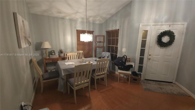 dining space with baseboards, a notable chandelier, wood finished floors, and lofted ceiling