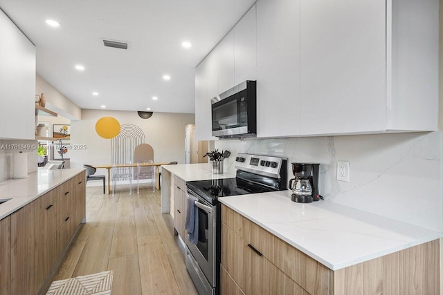 509 NE 29th St, Wilton Manors, FL 33334 - kitchen featuring stainless steel appliances, modern cabinets, light wood-type flooring, recessed lighting, and white cabinets