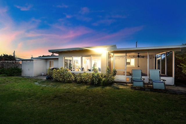 509 NE 29th St, Wilton Manors, FL 33334 - back of house at dusk featuring a sunroom, a yard, and stucco siding