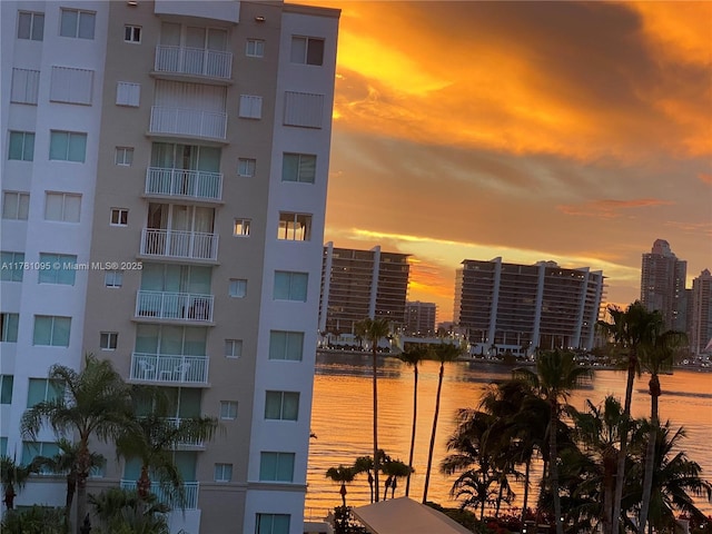 property at dusk with a city view and a water view