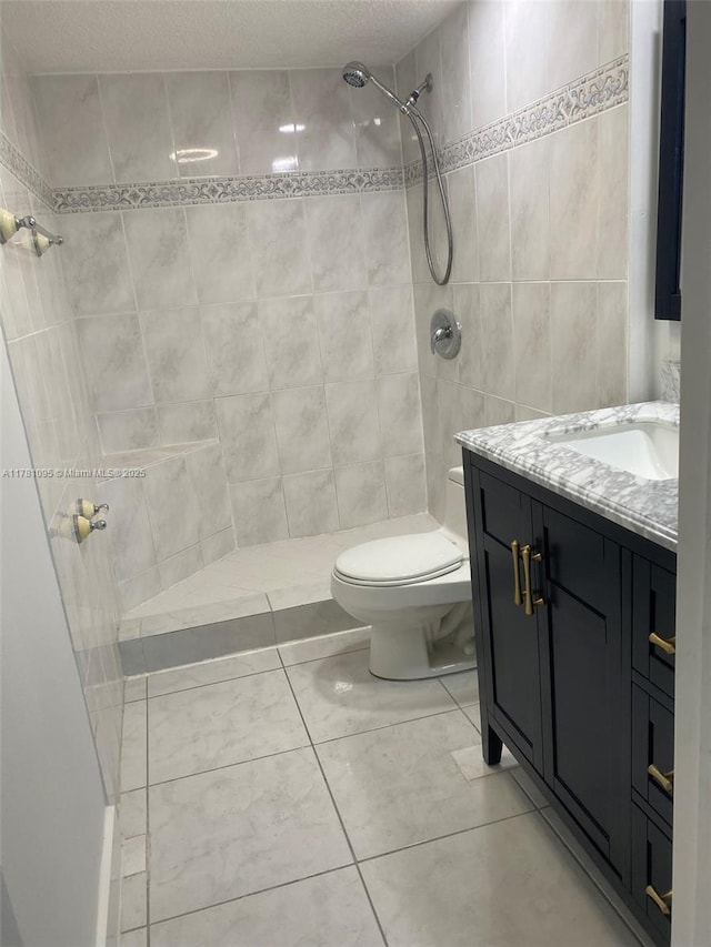 full bathroom with vanity, a tile shower, and toilet