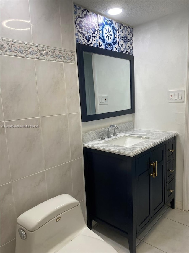 bathroom featuring vanity, tile patterned floors, a textured ceiling, toilet, and tile walls
