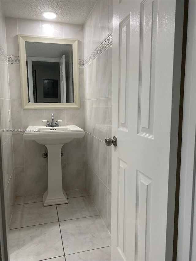 bathroom featuring a textured ceiling, tile patterned flooring, and tile walls