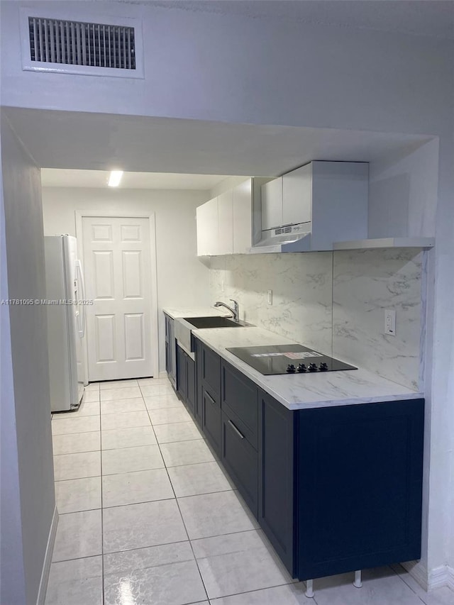 kitchen featuring visible vents, freestanding refrigerator, under cabinet range hood, black electric stovetop, and decorative backsplash