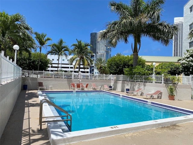 community pool with a patio area and fence