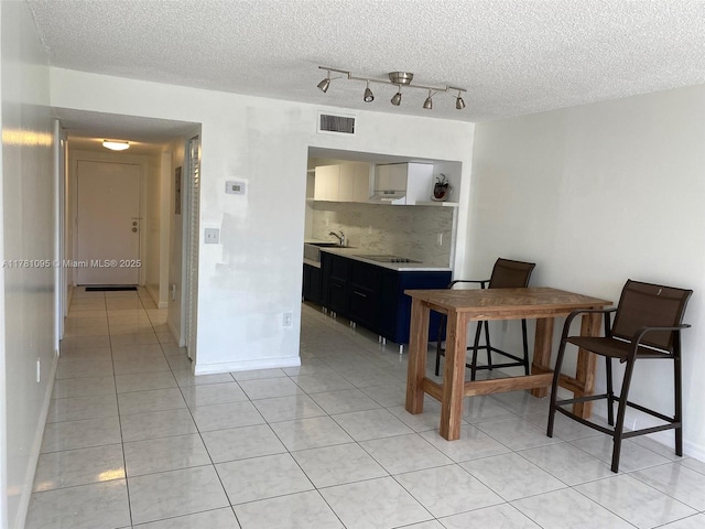 dining area with visible vents, a textured ceiling, baseboards, and light tile patterned flooring