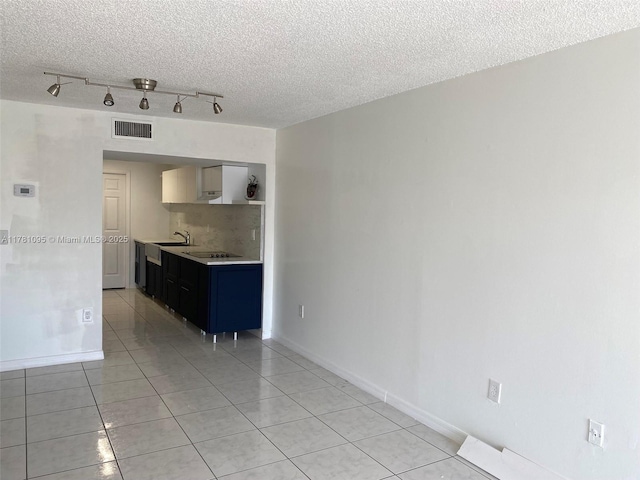 interior space with light tile patterned floors, a textured ceiling, visible vents, a sink, and light countertops
