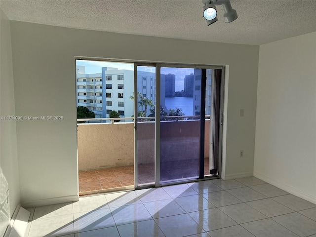 unfurnished room with tile patterned floors, baseboards, and a textured ceiling