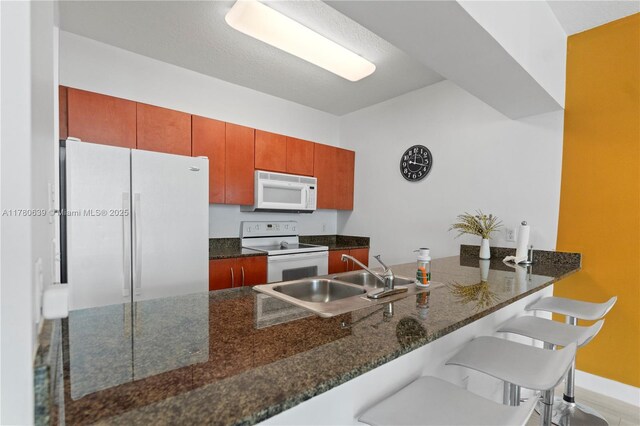 1200 Brickell Bay Dr Ph 4218, Miami, FL 33131 - kitchen featuring white appliances, a sink, a peninsula, a breakfast bar area, and dark stone countertops