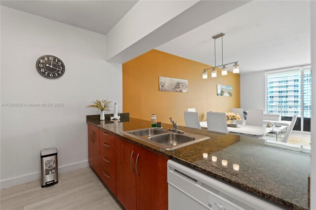 1200 Brickell Bay Dr Ph 4218, Miami, FL 33131 - kitchen with white dishwasher, a sink, baseboards, decorative light fixtures, and a peninsula