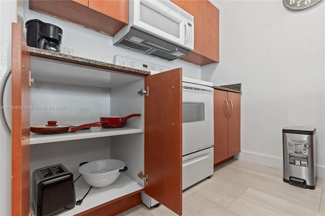 1200 Brickell Bay Dr Ph 4218, Miami, FL 33131 - kitchen featuring white microwave, brown cabinetry, light wood-style floors, and baseboards