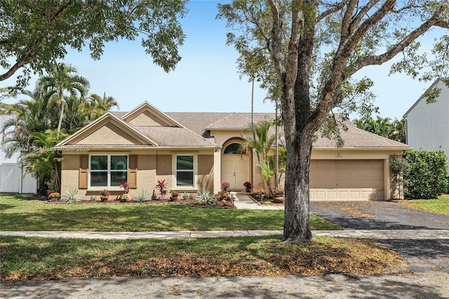 ranch-style house featuring an attached garage, driveway, stucco siding, and a front lawn