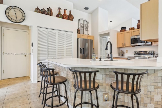 kitchen featuring a peninsula, appliances with stainless steel finishes, light tile patterned flooring, and light countertops
