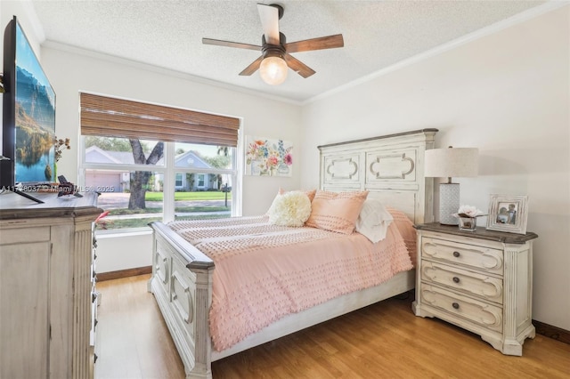 bedroom featuring ceiling fan, light wood-type flooring, ornamental molding, and a textured ceiling