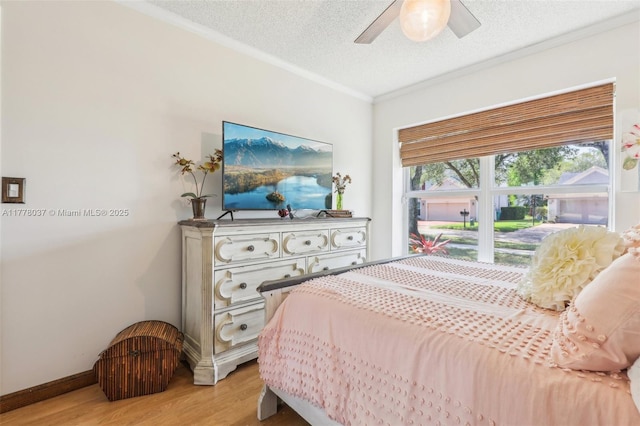 bedroom with crown molding, light wood-style flooring, a textured ceiling, a ceiling fan, and baseboards
