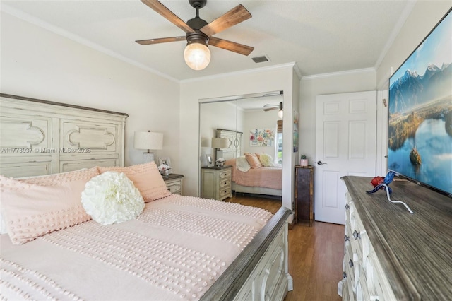 bedroom with a closet, ornamental molding, dark wood-type flooring, visible vents, and ceiling fan