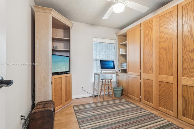 office featuring light wood-style floors, ceiling fan, and a textured ceiling