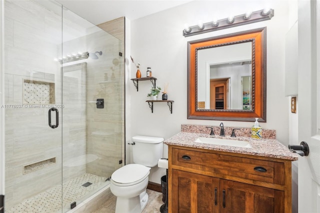 full bath featuring toilet, a stall shower, vanity, and baseboards