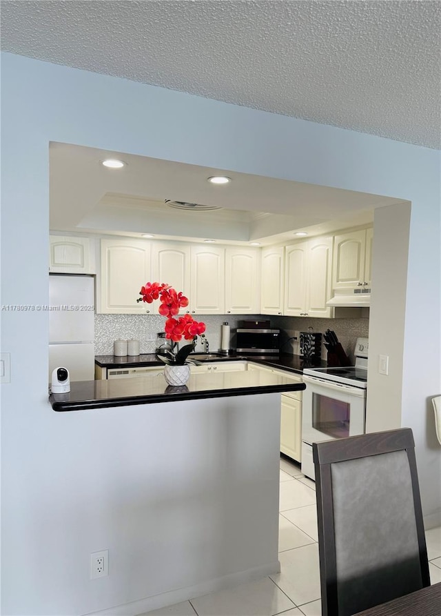 2101 S Ocean Dr Unit 1902, Hollywood, FL 33019 - kitchen with under cabinet range hood, dark countertops, white appliances, light tile patterned flooring, and tasteful backsplash