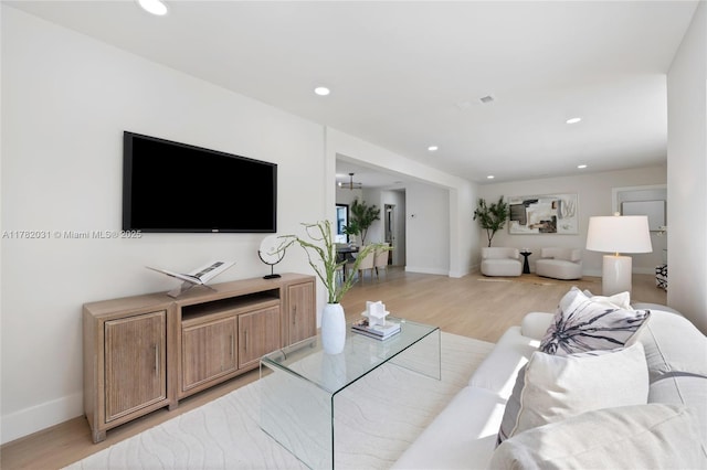living room featuring baseboards, visible vents, light wood-style flooring, and recessed lighting
