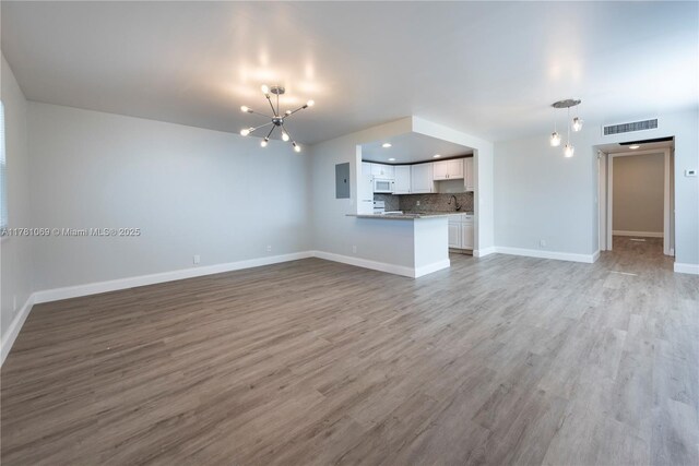 494 Monaco K Unit 494, Delray Beach, FL 33446 - unfurnished living room with a notable chandelier, baseboards, electric panel, visible vents, and wood finished floors