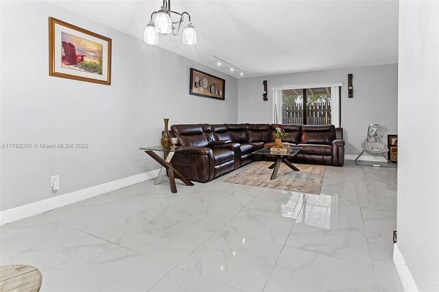 living room with track lighting, marble finish floor, baseboards, and an inviting chandelier